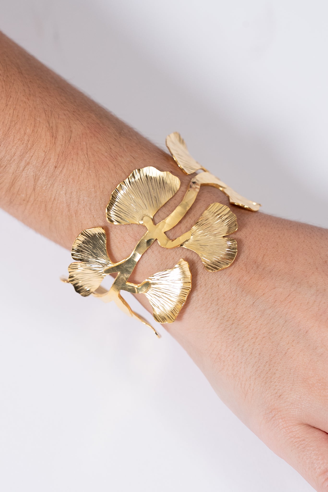 Pulsera dorada con piezas grandes en forma de hojas unidas entre sí.