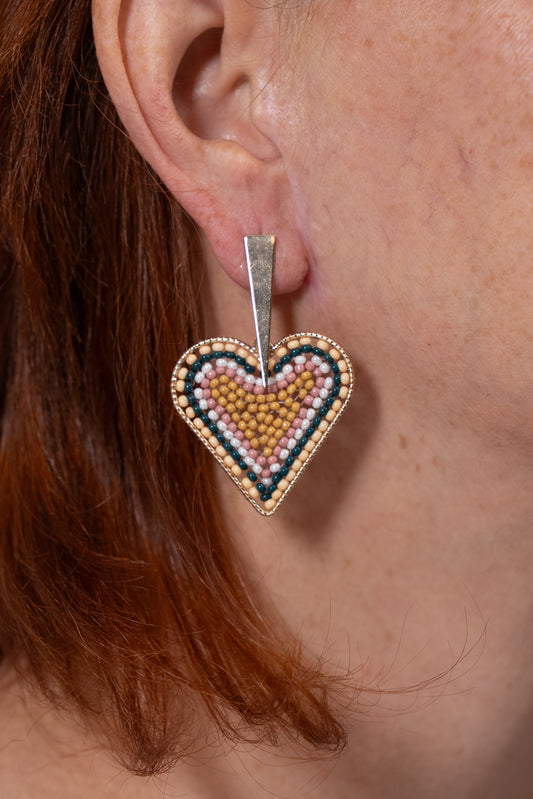 Aros en forma de corazón con diseño tejido en tonos dorado, negro y rosa.