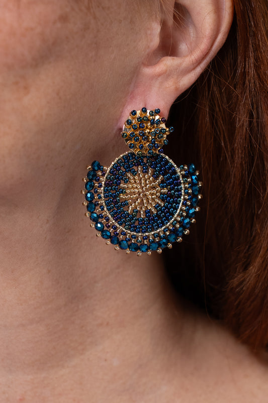 Aros circulares en tonos azul y dorado con diseño tejido y detalle en la parte superior.
