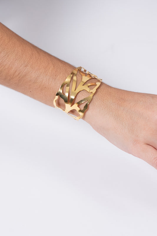 Pulsera dorada con diseño calado estilo hoja.