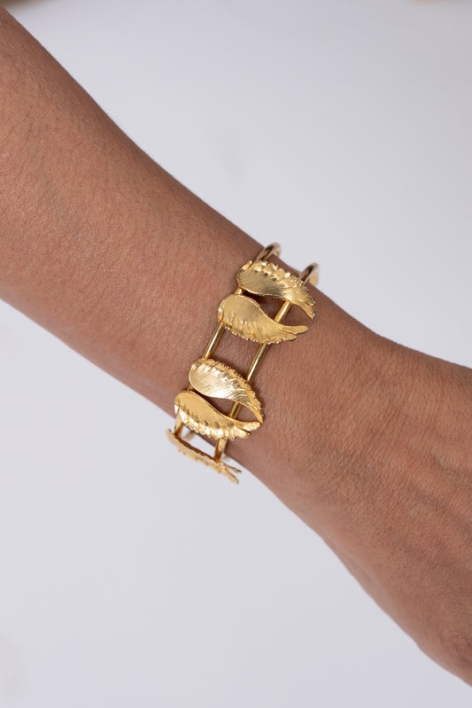 Pulsera dorada con piezas tipo hoja unidas por eslabones.