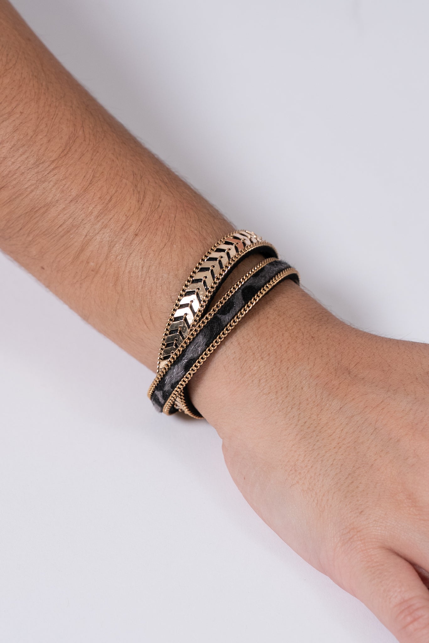 Pulsera triple en tonos negro, dorado y plateado con detalles metálicos.