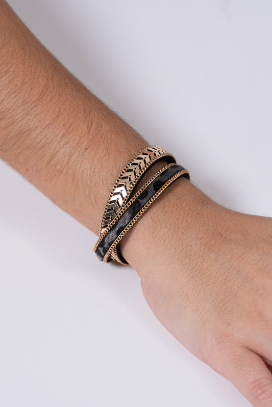Pulsera triple en tonos negro, dorado y plateado con detalles metálicos.