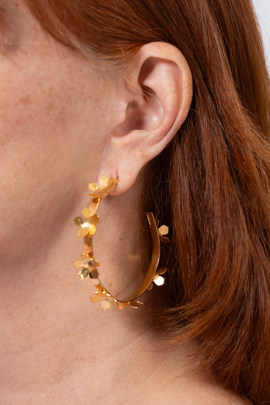 Aros dorados tipo argolla con pequeños detalles en forma de hojitas alrededor.