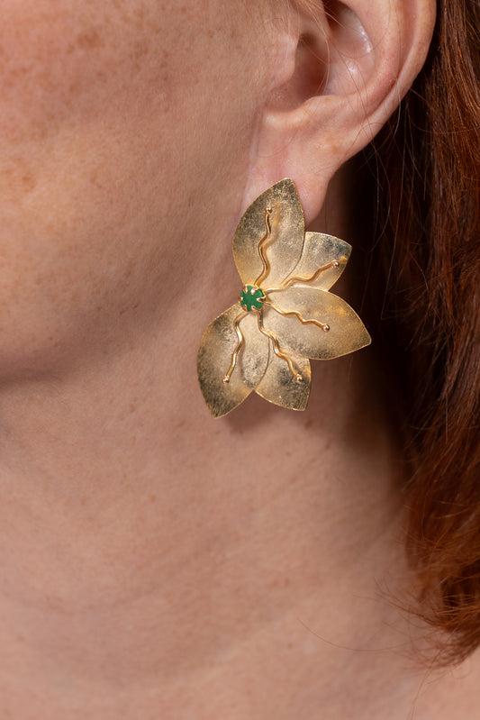 Aros dorados en forma de flor con centro verde y detalles en relieve.