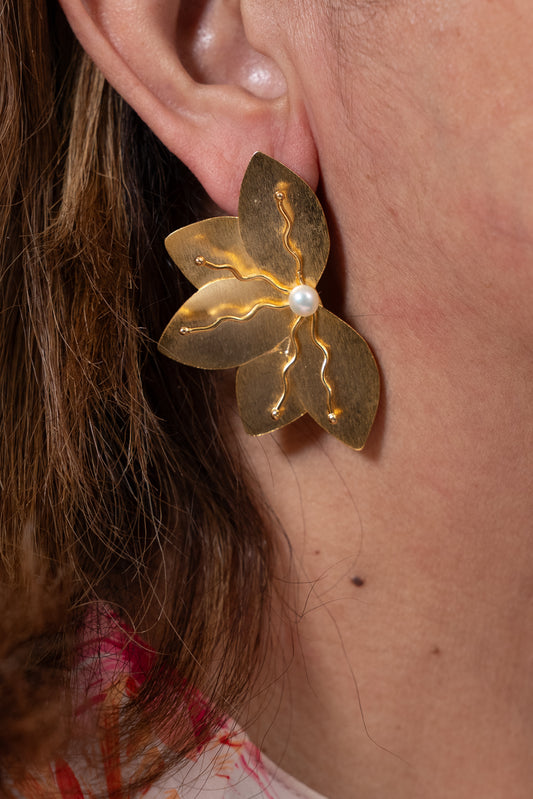 Aros dorados en forma de flor con centro claro y pétalos texturados.