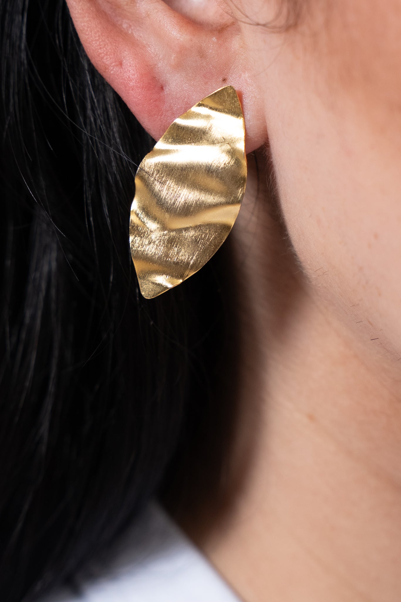 Aros dorados pequeños con pieza metálica en forma de hoja.