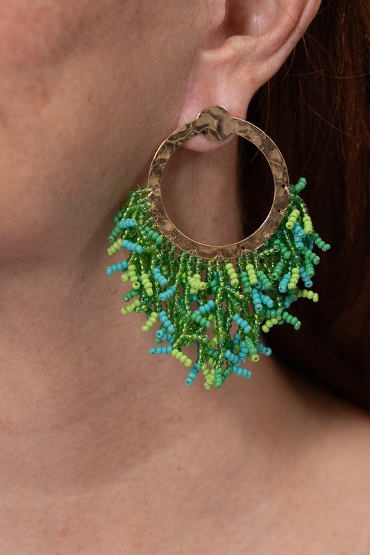 Aros tipo argolla con base dorada y flecos verdes tejidos alrededor.
