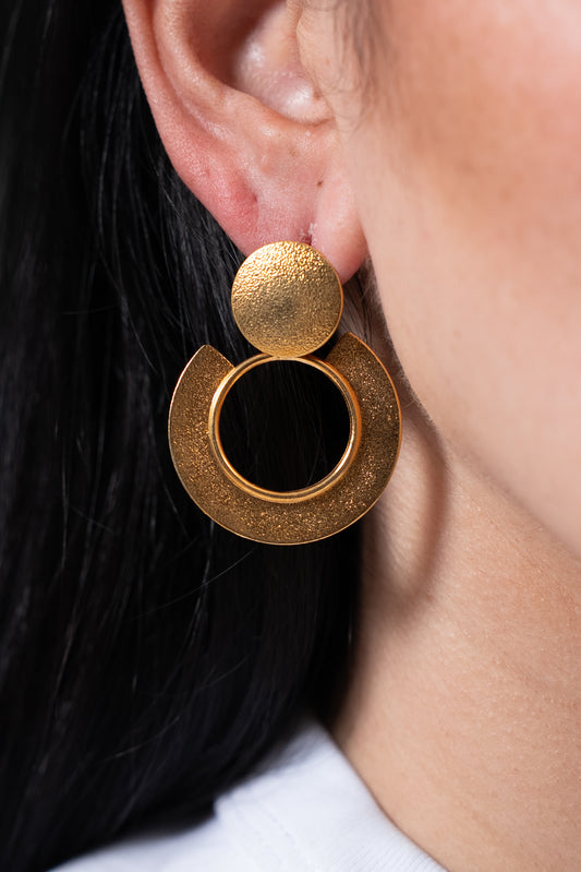 Aros dorados con base redonda y diseño circular doble colgante.