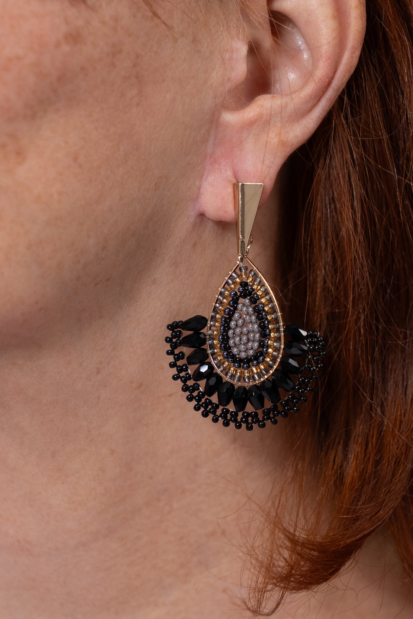 Aros en forma de gota con detalle central brillante y diseño decorativo negro en la parte inferior.